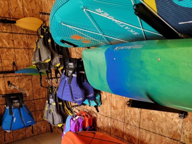 boating Kayaks, paddleboards, and life vests stored in The Paddle Vault garage at Kings Landing, showcasing colorful equipment for outdoor adventures on Moosehead Lake.